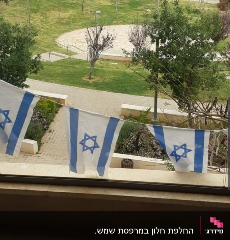 חלון זכוכית עם דגלים ישראליים תלויים